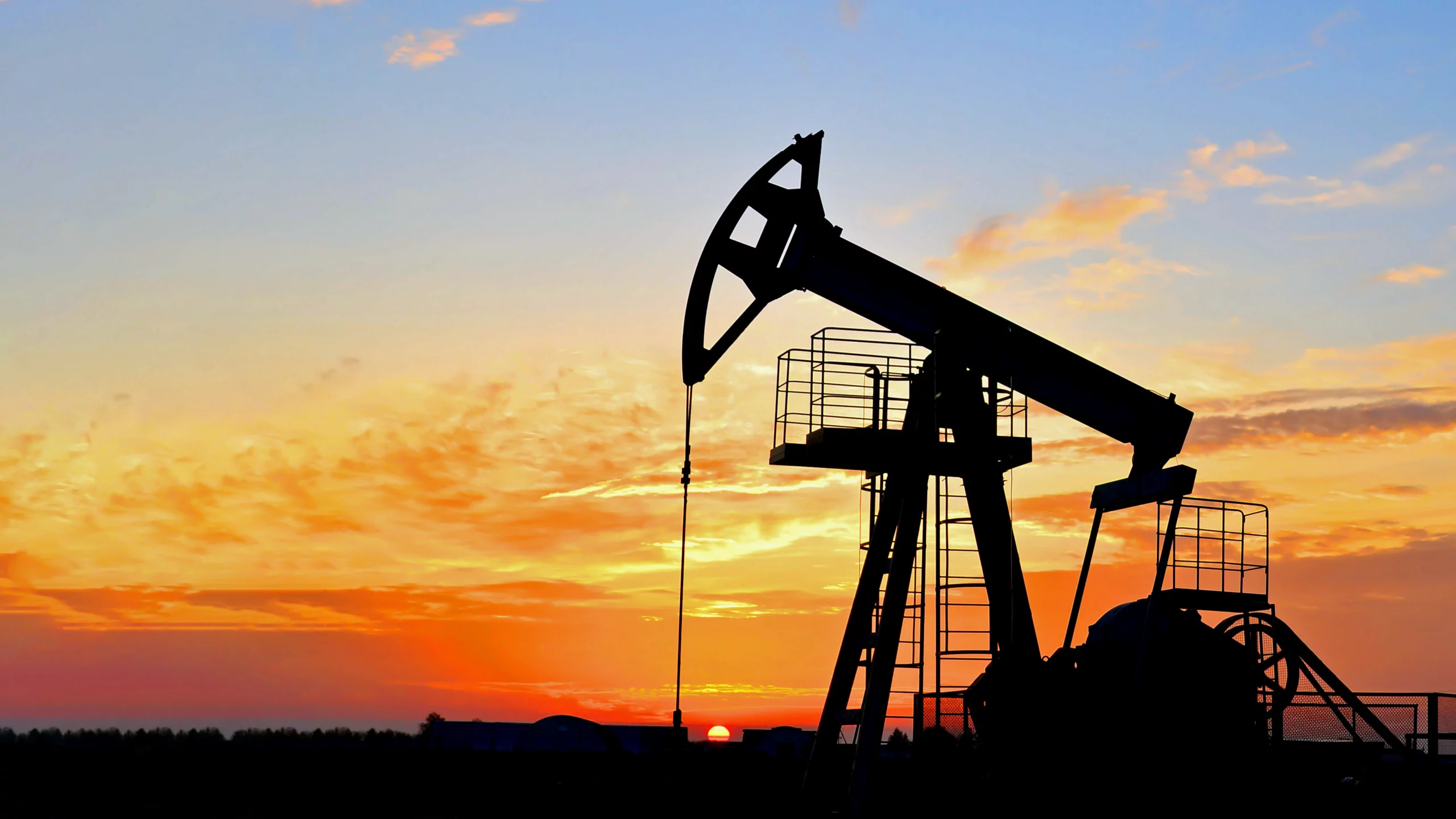 Pumpjack pumping for oil in silhouette against the orange sky of a sunset